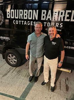 Two men are standing next to each other in front of a van.