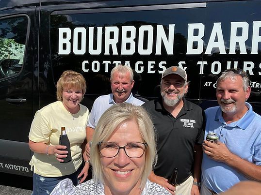 A group of people standing in front of a bourbon bar cottages and tours van
