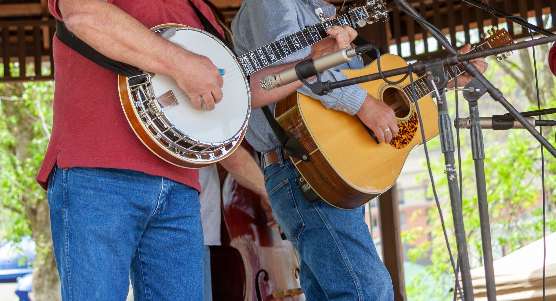 Two musicians playing banjo and guitar on an outdoor stage.