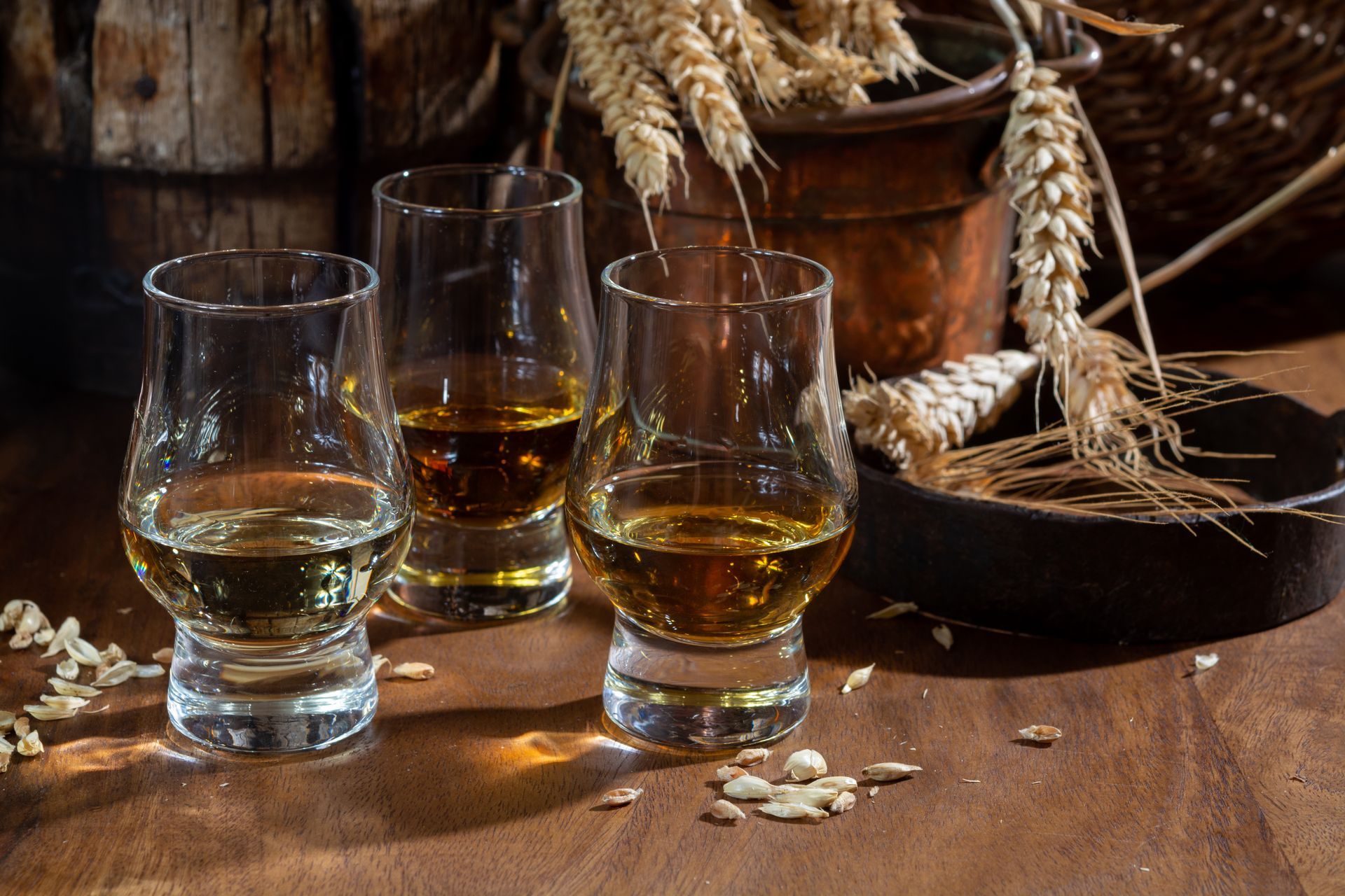 Four glasses of whiskey are sitting on a wooden table.