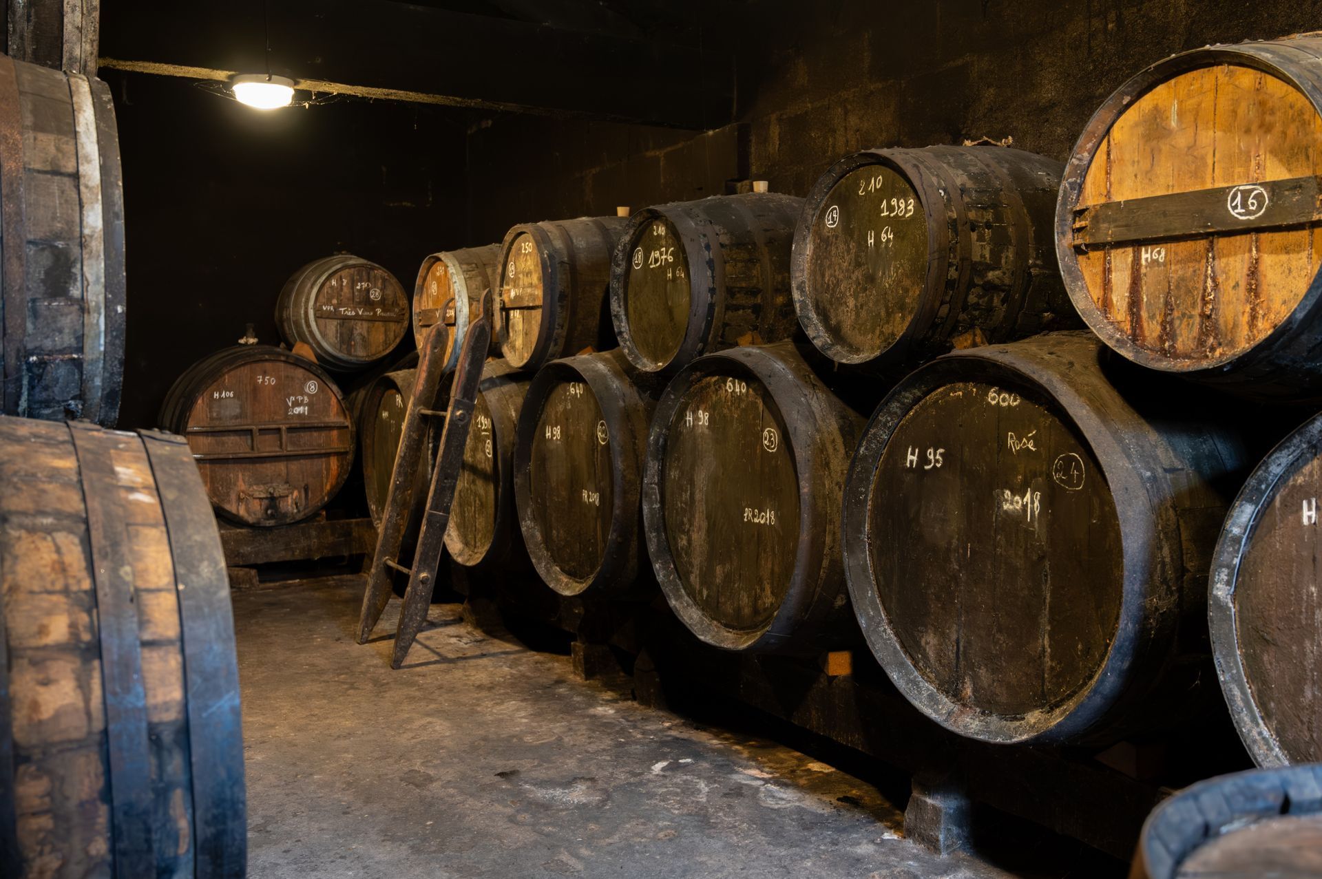 A row of wooden barrels are stacked on top of each other in a dark room.