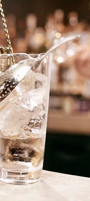 A glass of water with ice and a spoon in it.