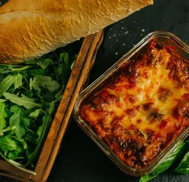 A fresh baked lasagna and bread ready to be served