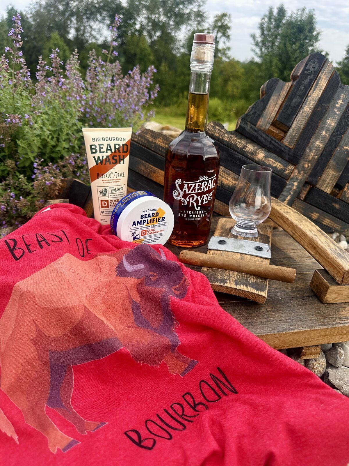 Beast of Bourbon t-shirt, Buffalo Trace beard wash, beard amplifier, and Glencairn tasting glass styled on an outdoor table at Bourbon Barrel Cottages