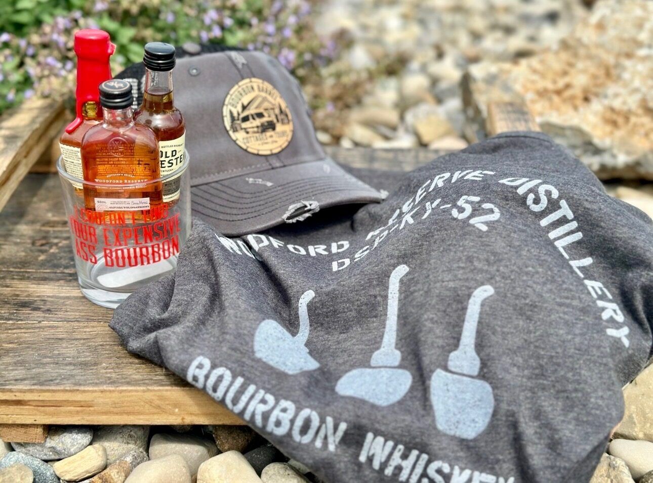 Miniature bottles of Woodford Reserve, Old Forester, and Maker's Mark bourbon with a novelty rocks glass and Woodford Reserve Distillery t-shirt
