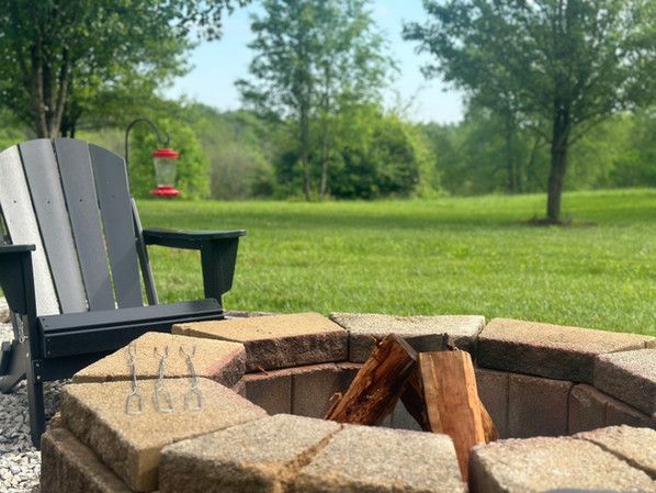 A chair is sitting next to a fire pit in a field.