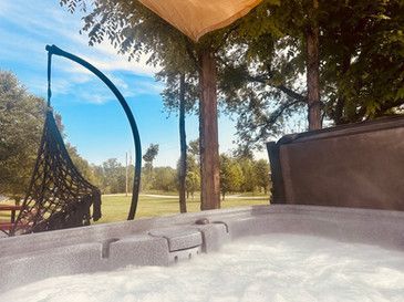 A hot tub is sitting under a canopy on a patio.