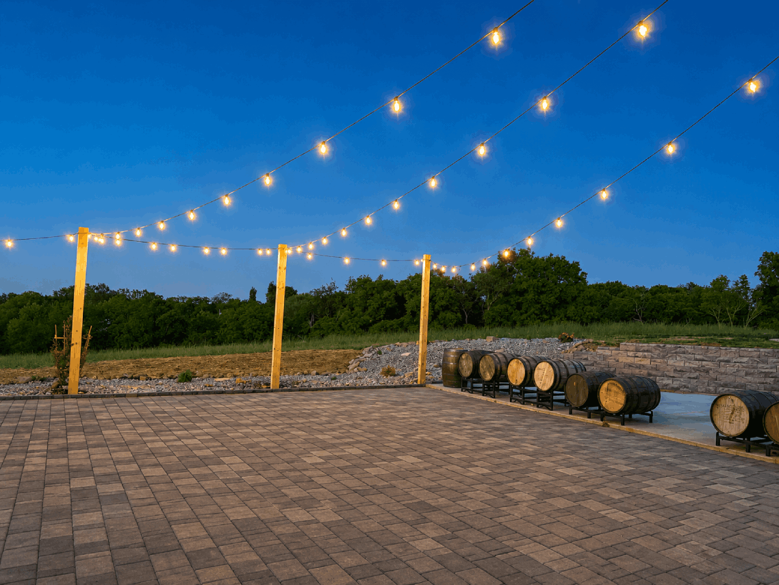 Open-air event patio at Bourbon Barrel Cottages with string lights, yellow posts, and bourbon barrel display