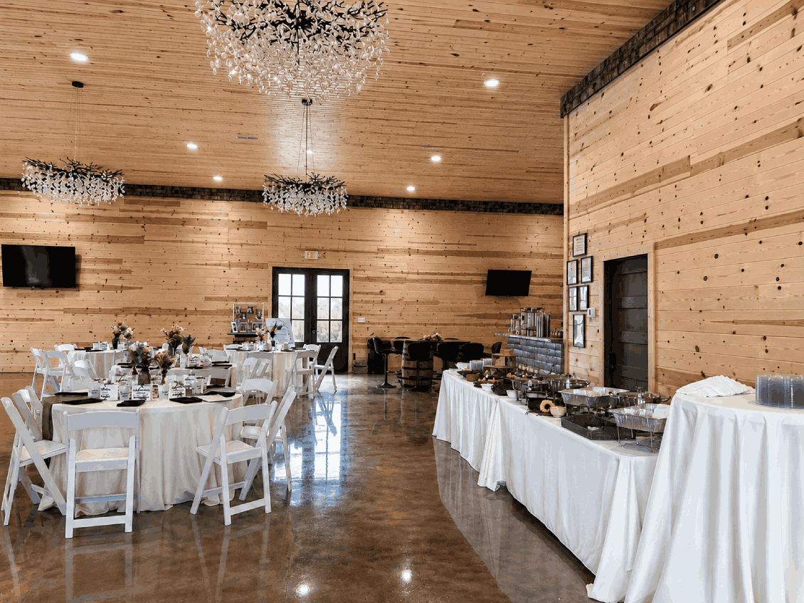Rustic barn reception hall at Bourbon Barrel Cottages with crystal chandeliers and elegant table settings