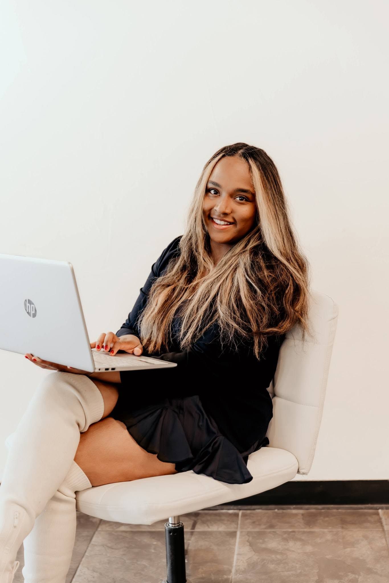 Woman seated with a laptop, smiling in a bright modern room