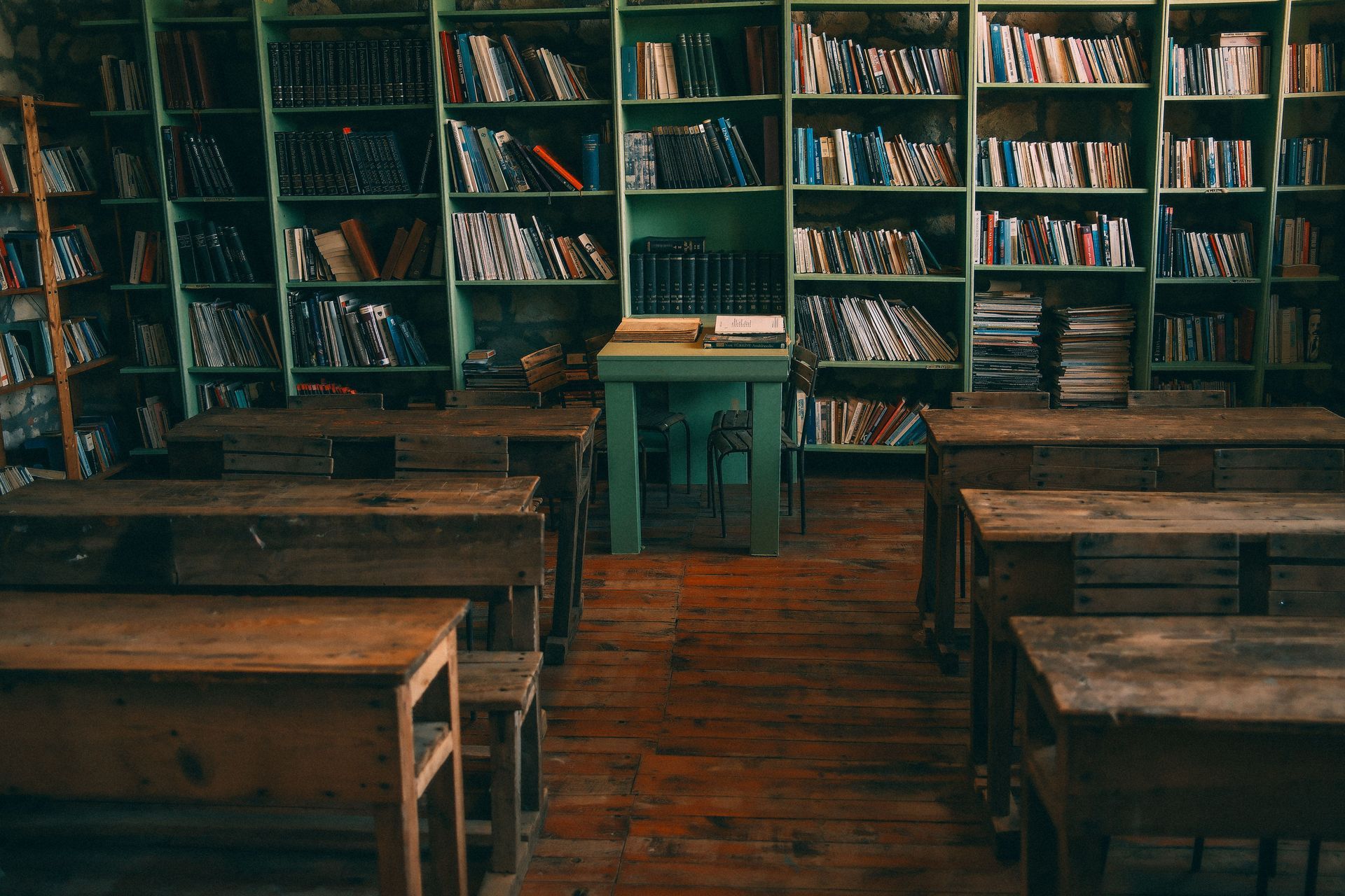 Rustic library classroom with wooden benches, bookshelves, and a central lectern under warm lighting