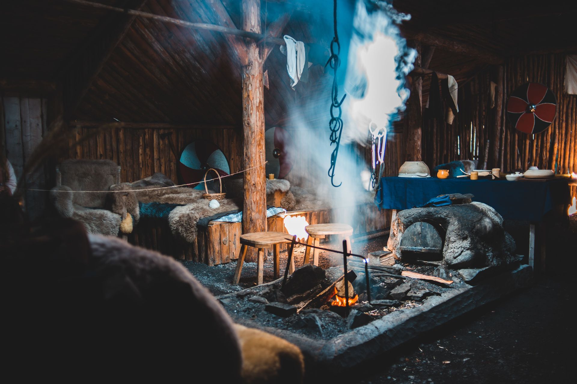 Cozy cabin interior with a lit wood stove, hanging kettle, and rustic log walls