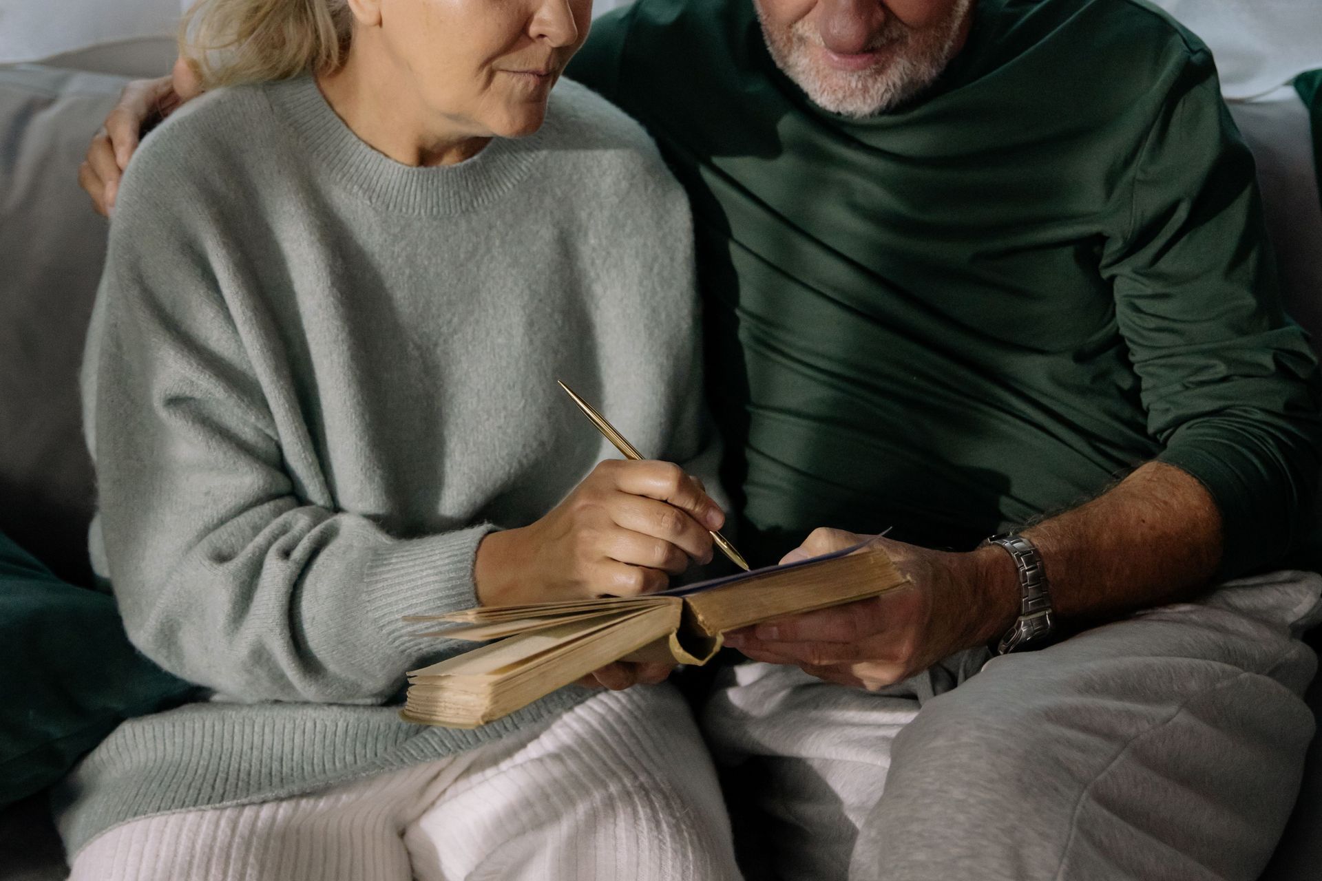 Two people sitting on a couch, sharing a notebook and pencil together