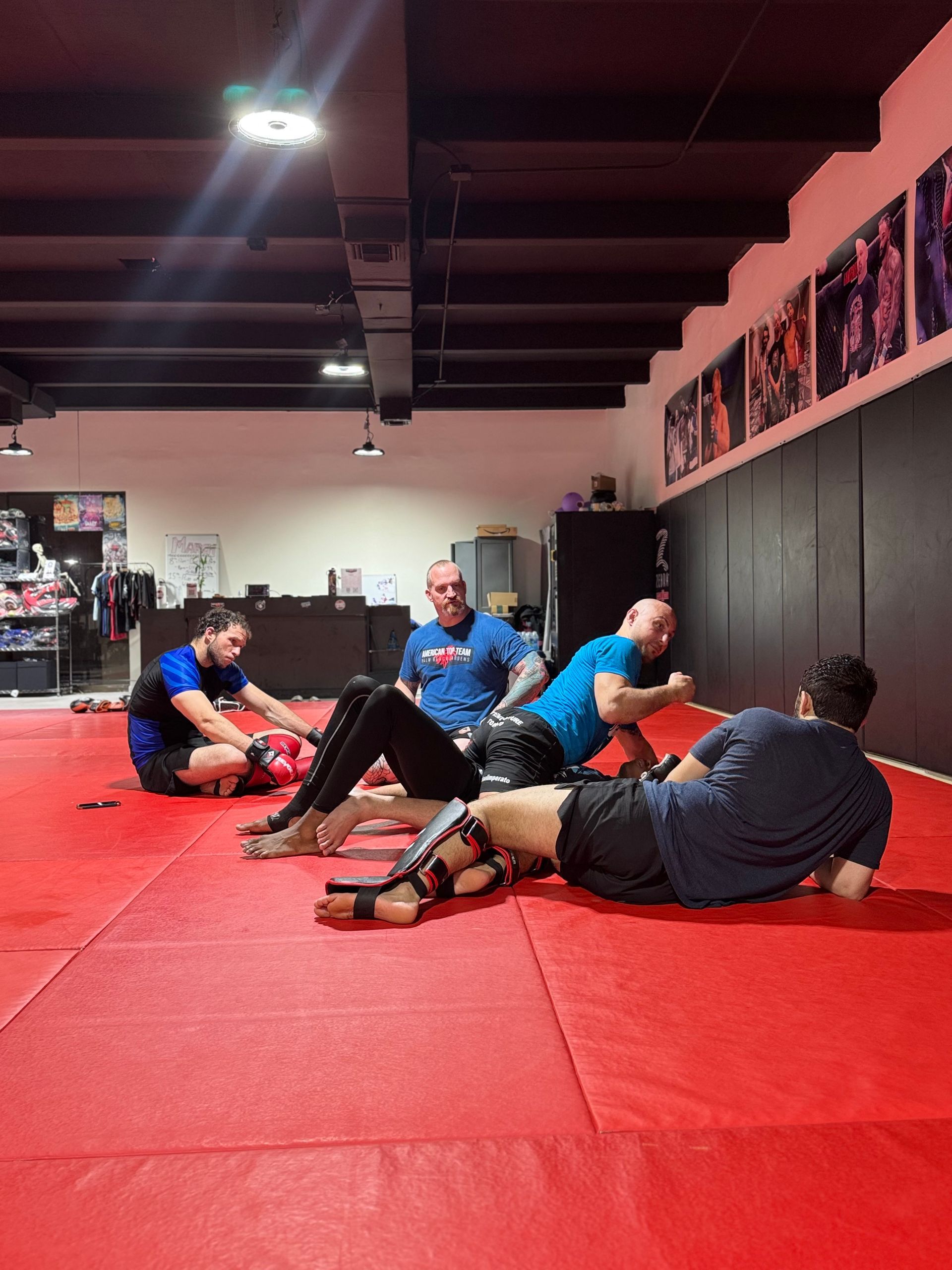 A group of men are sitting on a red mat in a gym.