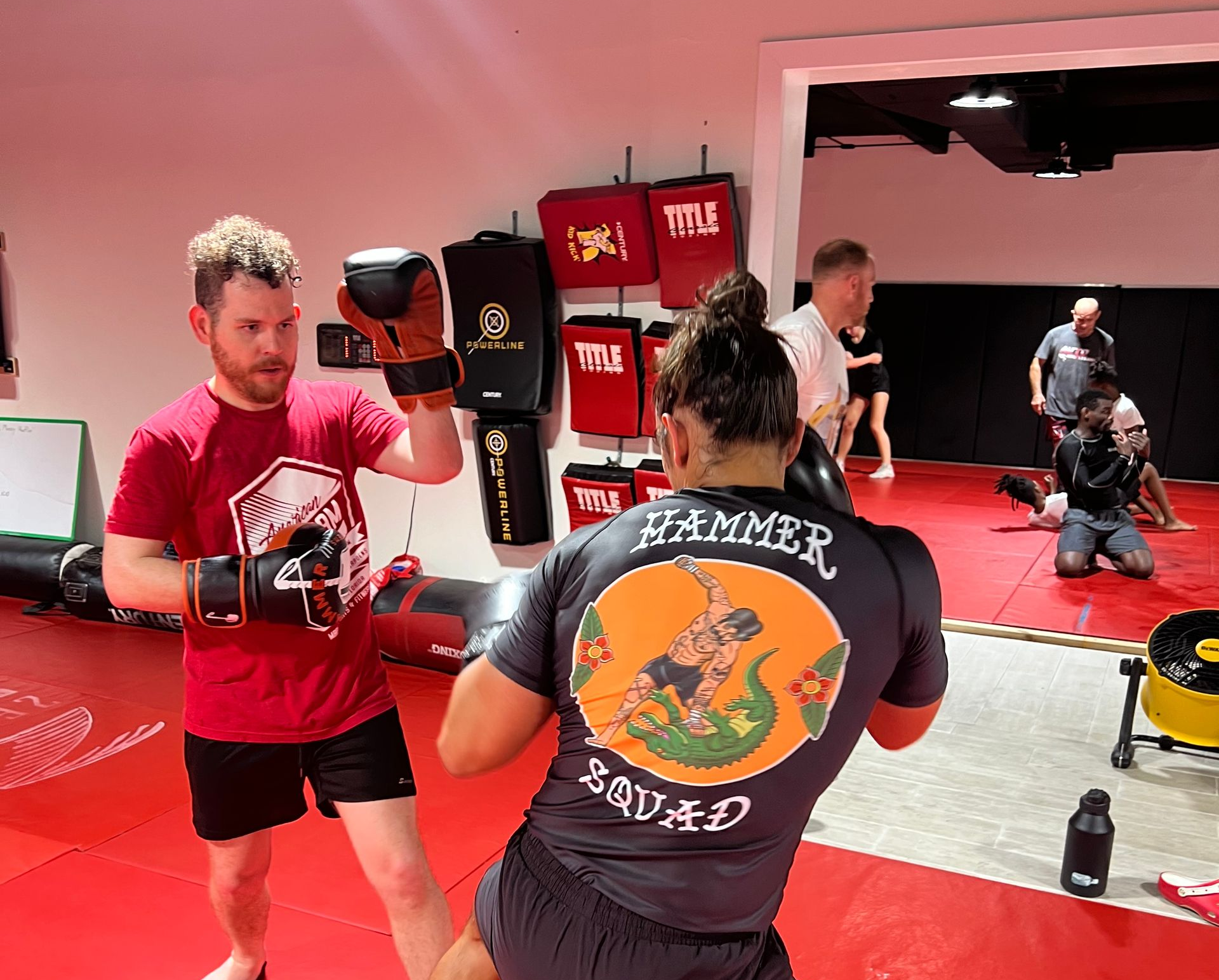 Three men are standing on a wrestling mat and one of them is wearing a yellow belt