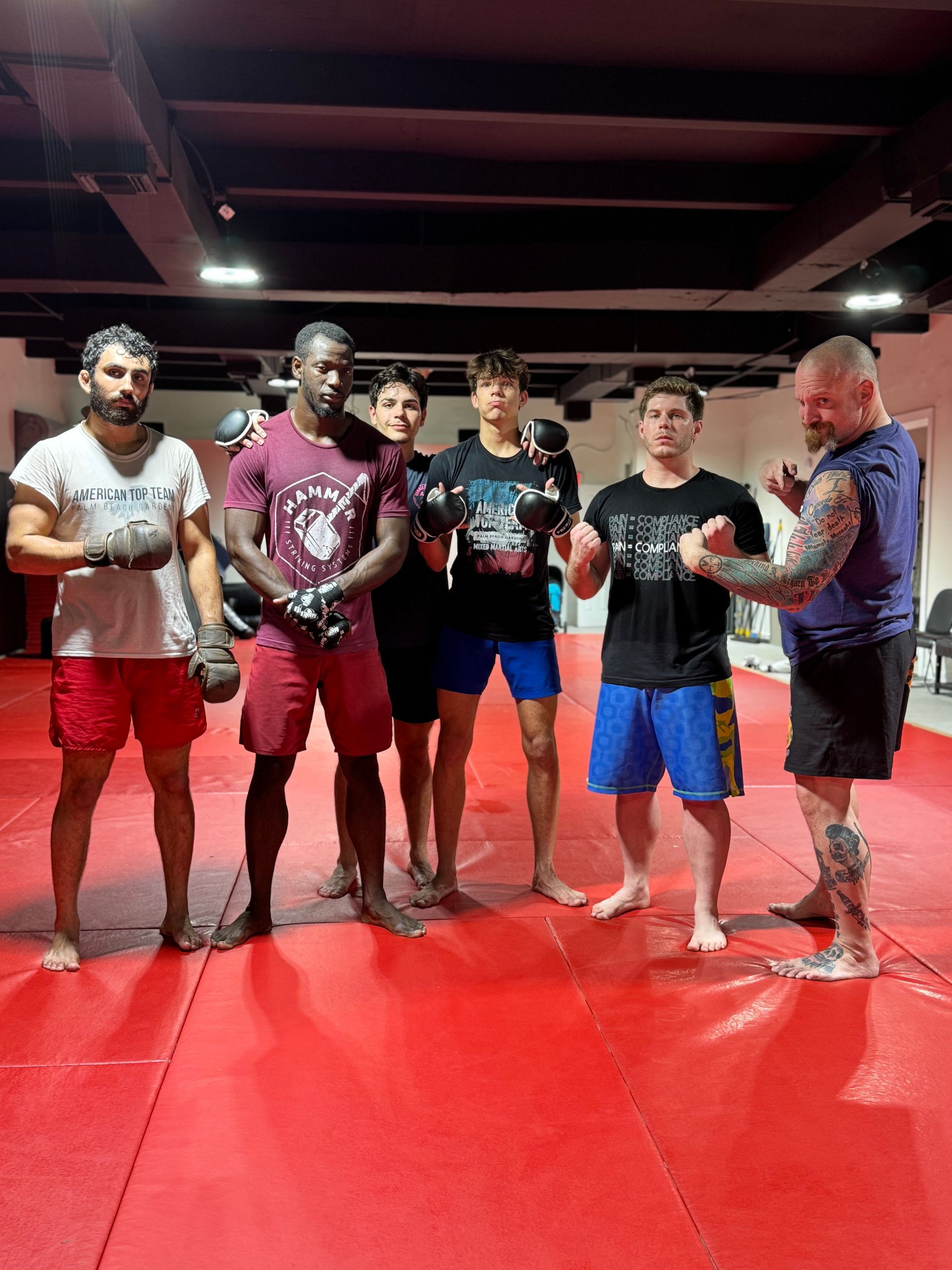 A group of men are standing on a red mat in a gym.
