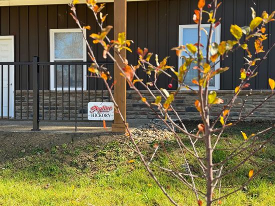 a tree in front of a house with a  sign