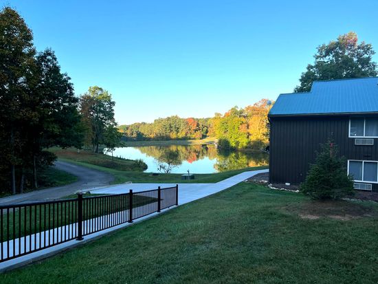 a house with a blue roof is sitting next to a lake .