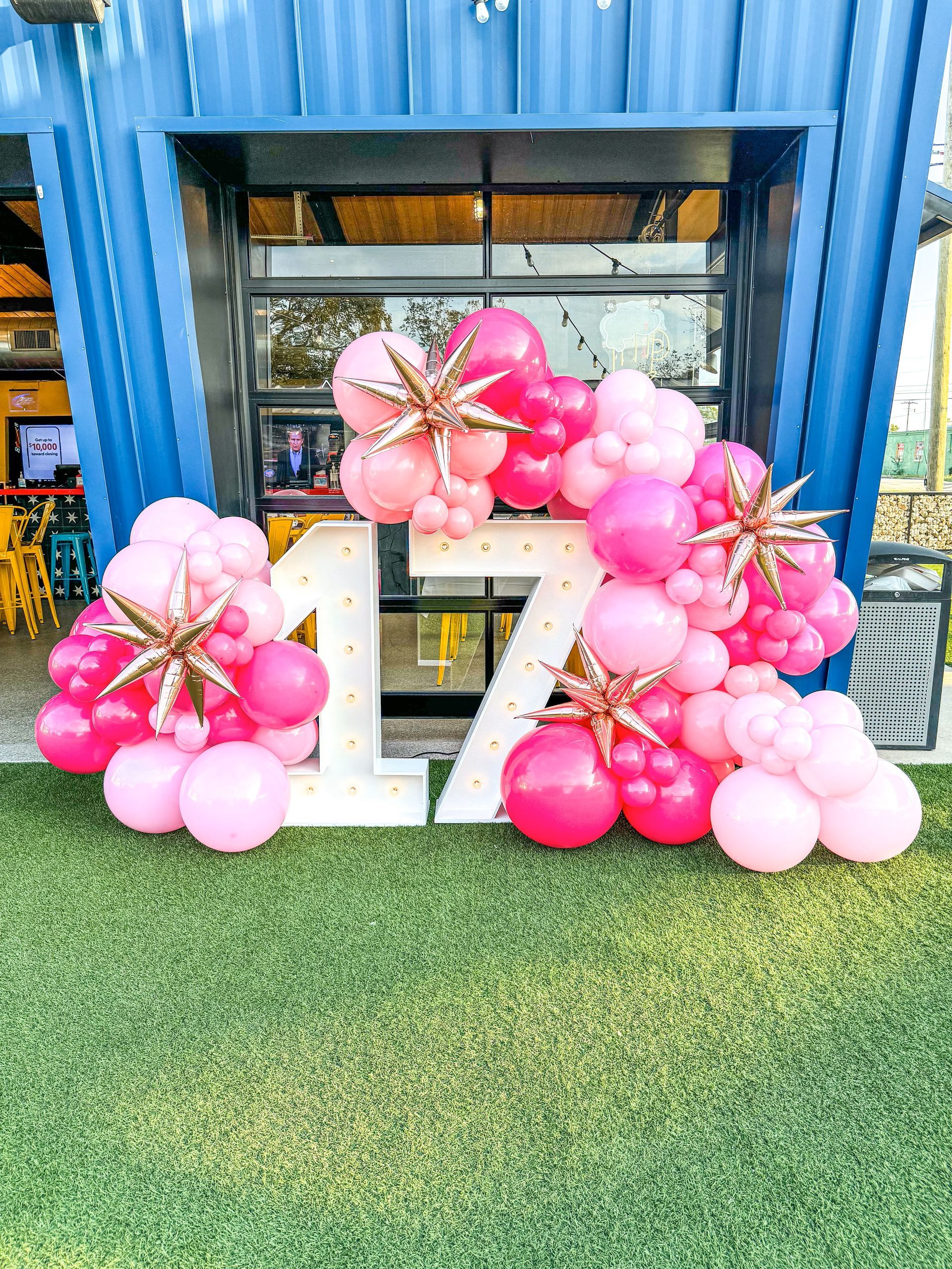 A bunch of pink balloons are sitting in front of a building.