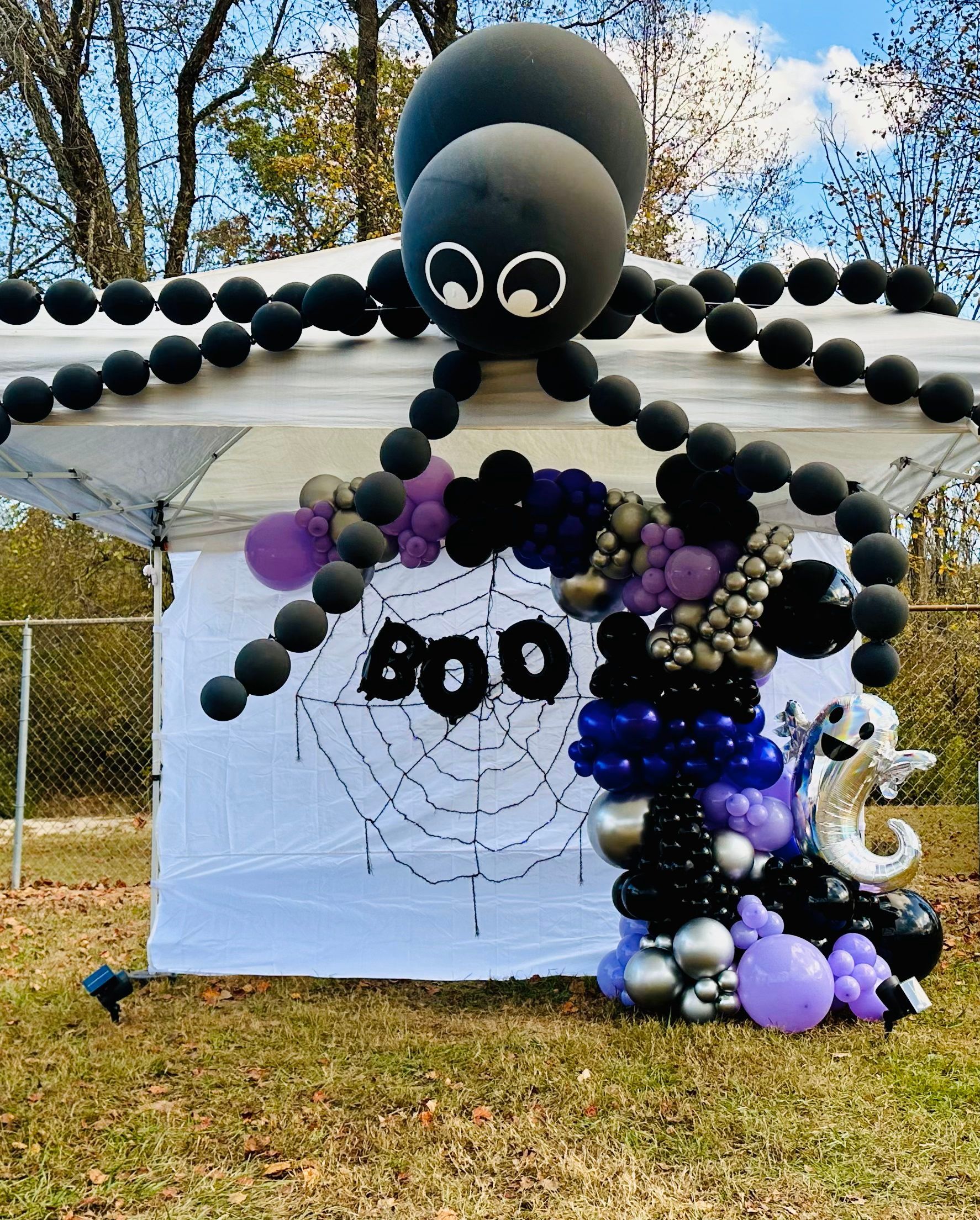 A tent with balloons and a spider on top of it.