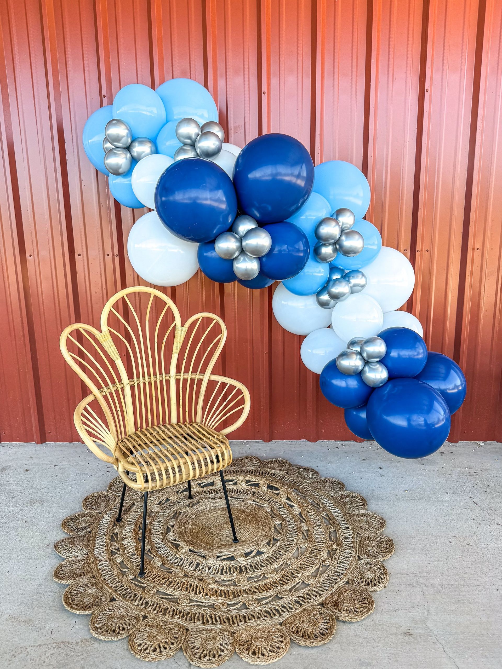 A wicker chair is sitting in front of a balloon arch.