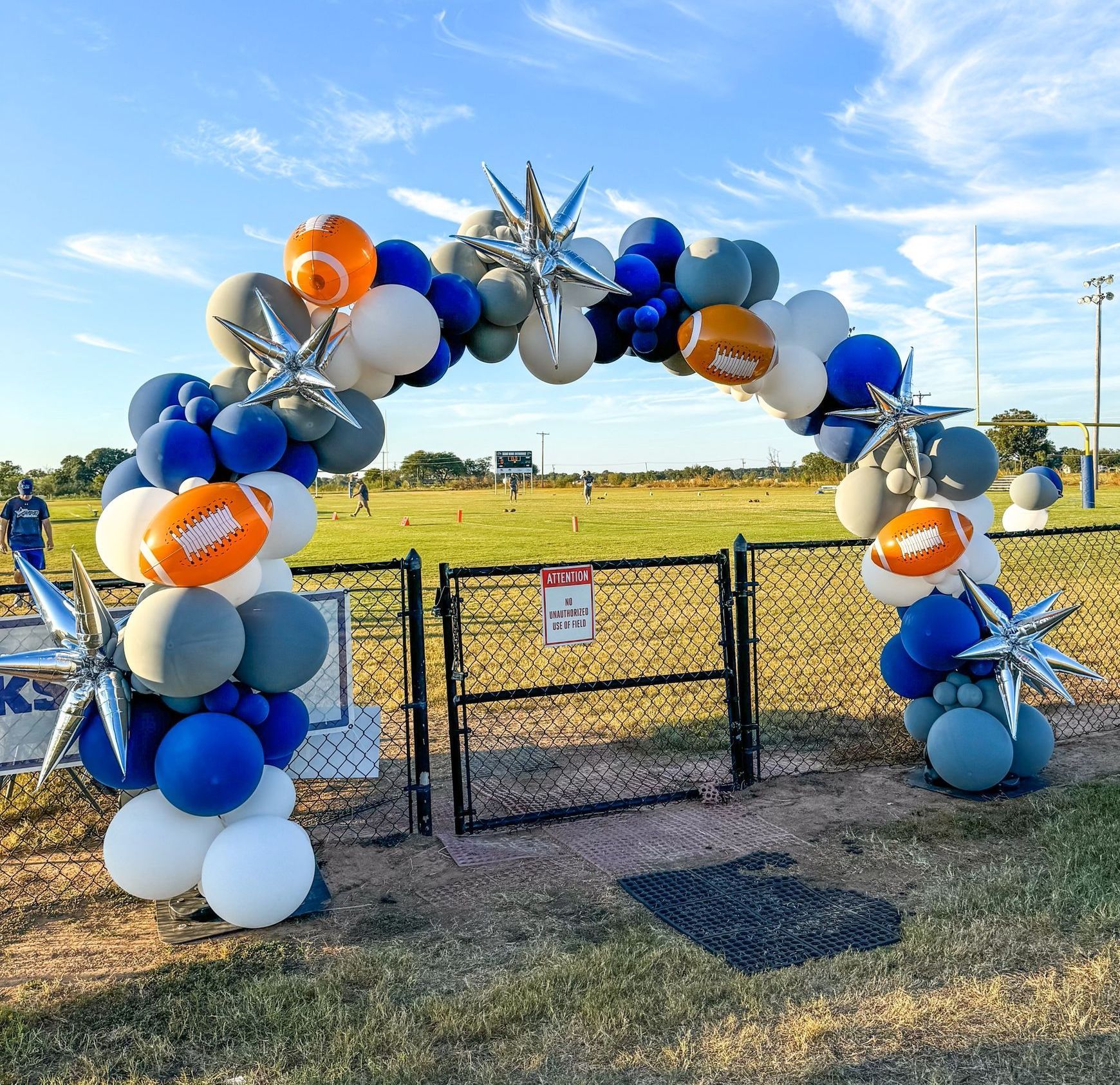 A bunch of balloons are sitting on top of a fence in a field.