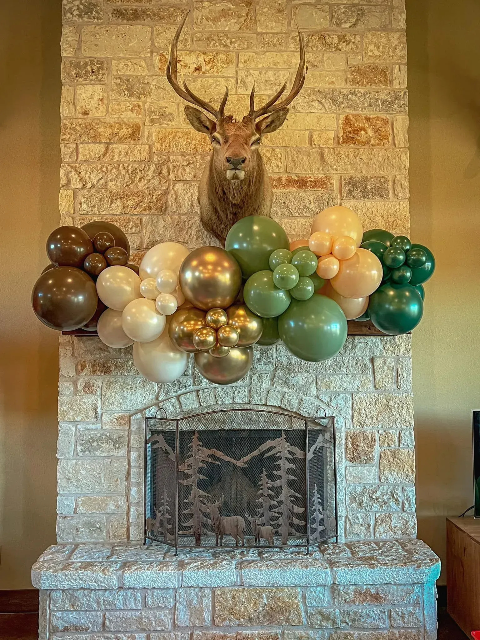 A fireplace decorated with balloons and a deer head.