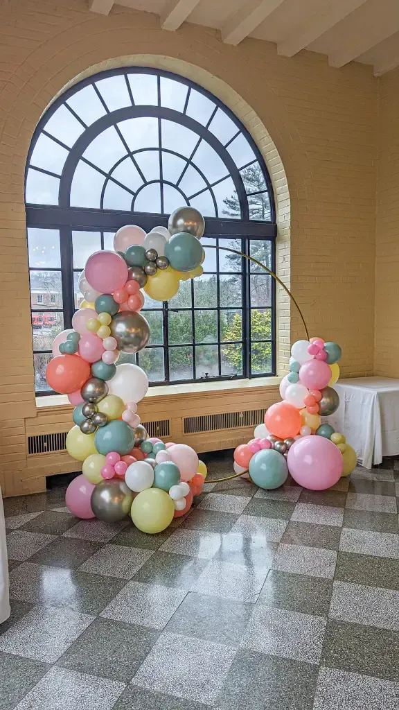 A bunch of balloons are sitting on the floor in front of a window.