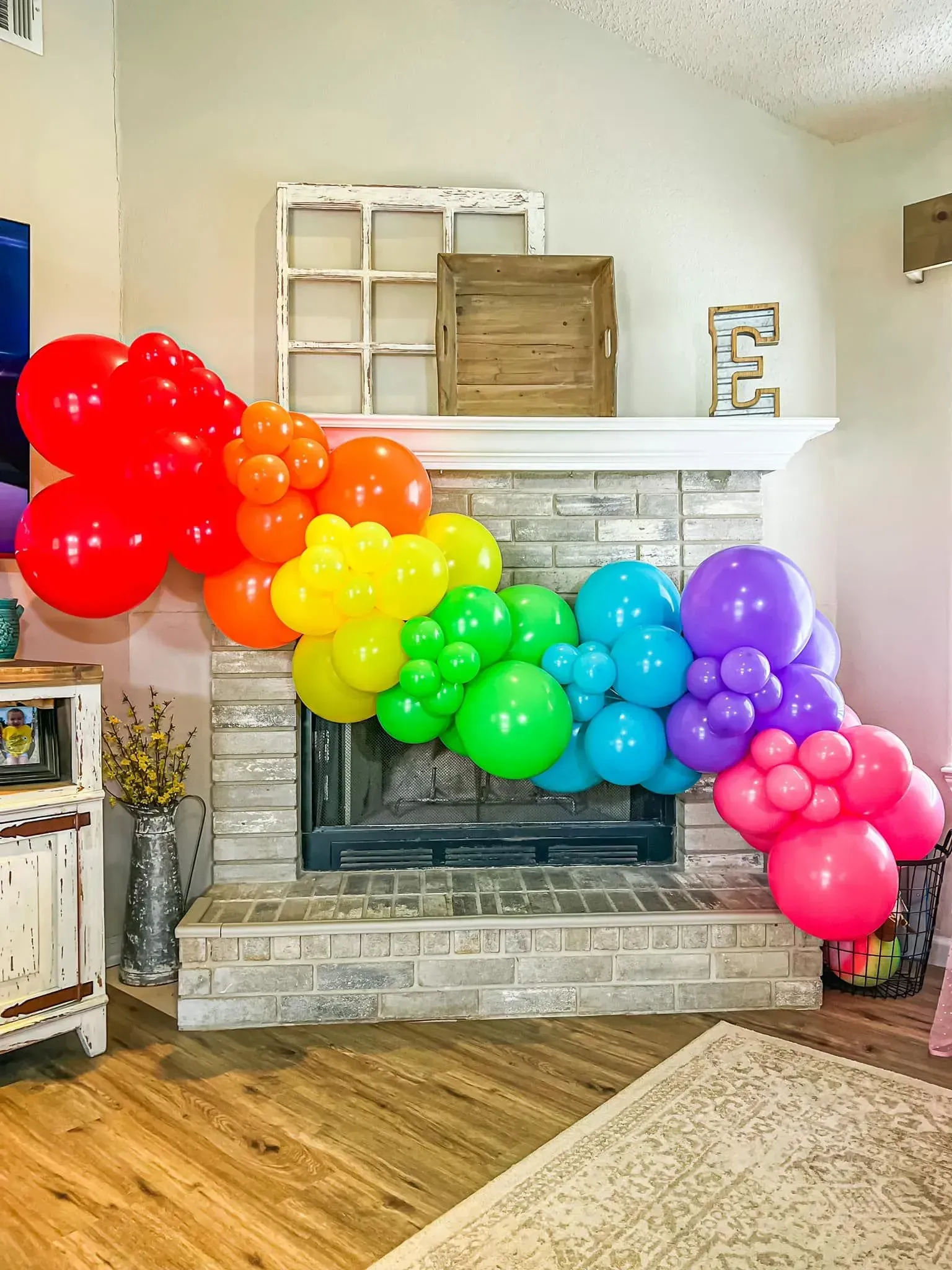 A living room with a fireplace decorated with balloons in the shape of a rainbow.
