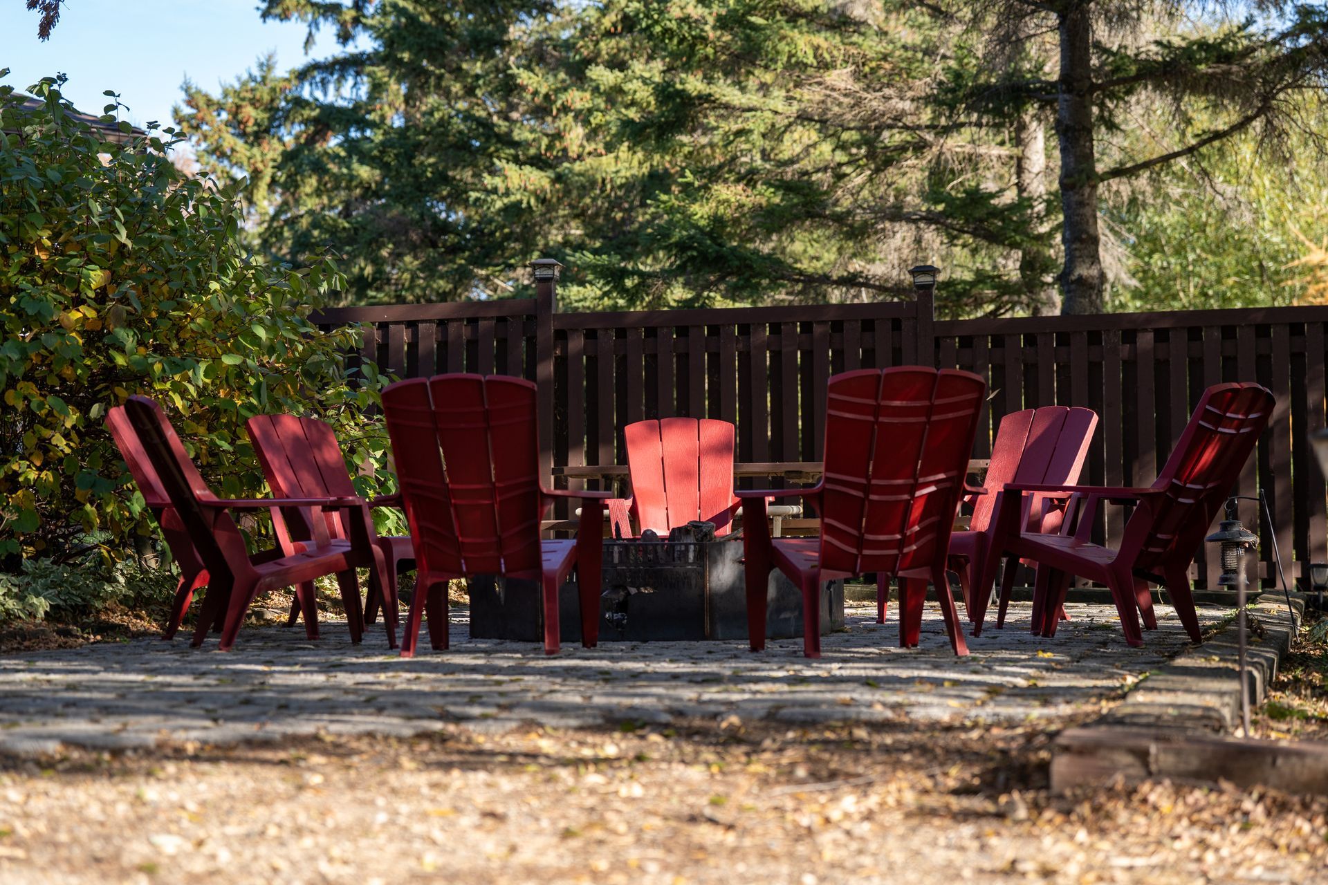 A group of red chairs are sitting around a fire pit.
