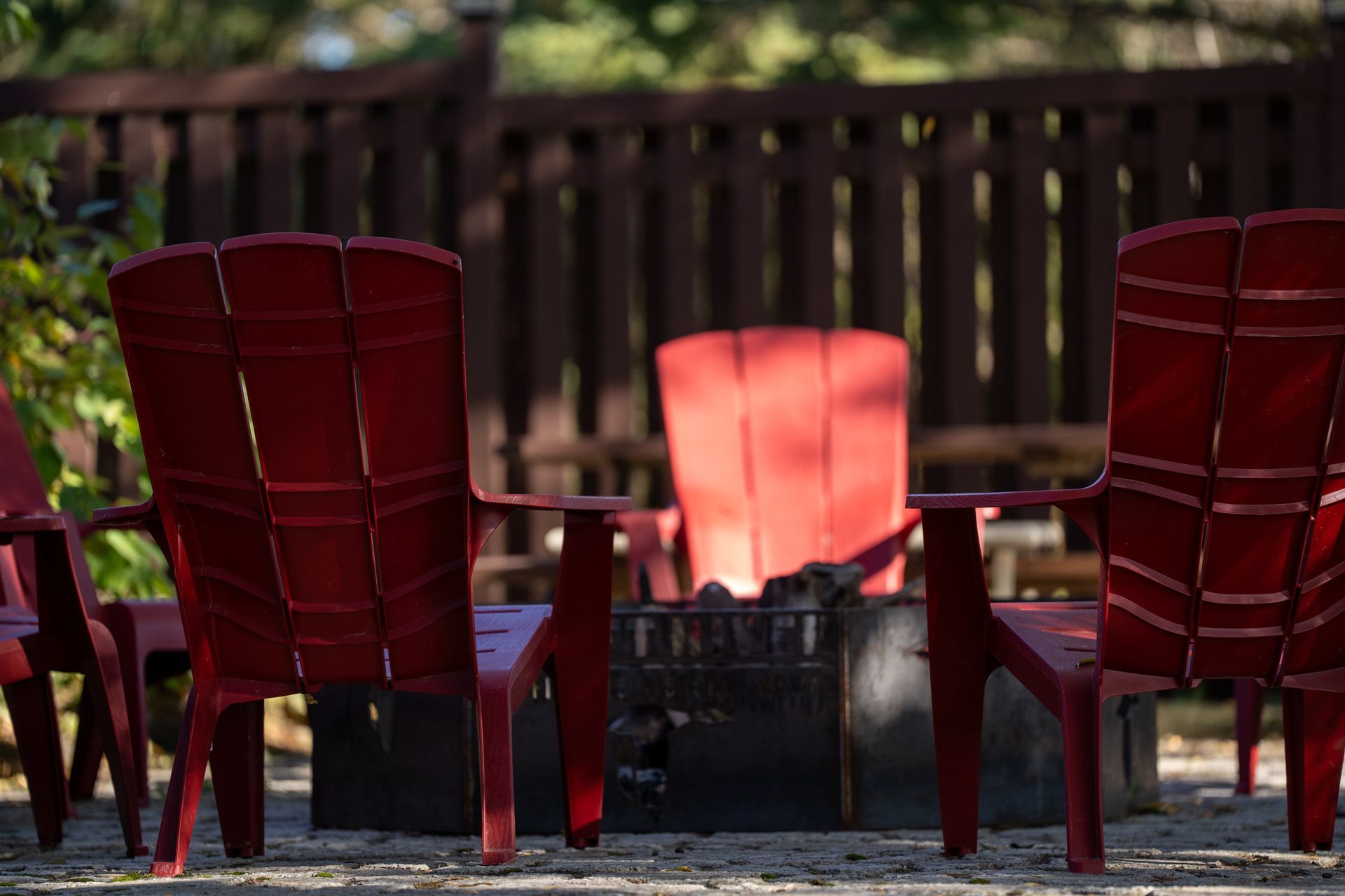 A group of red chairs are sitting around a fire pit.