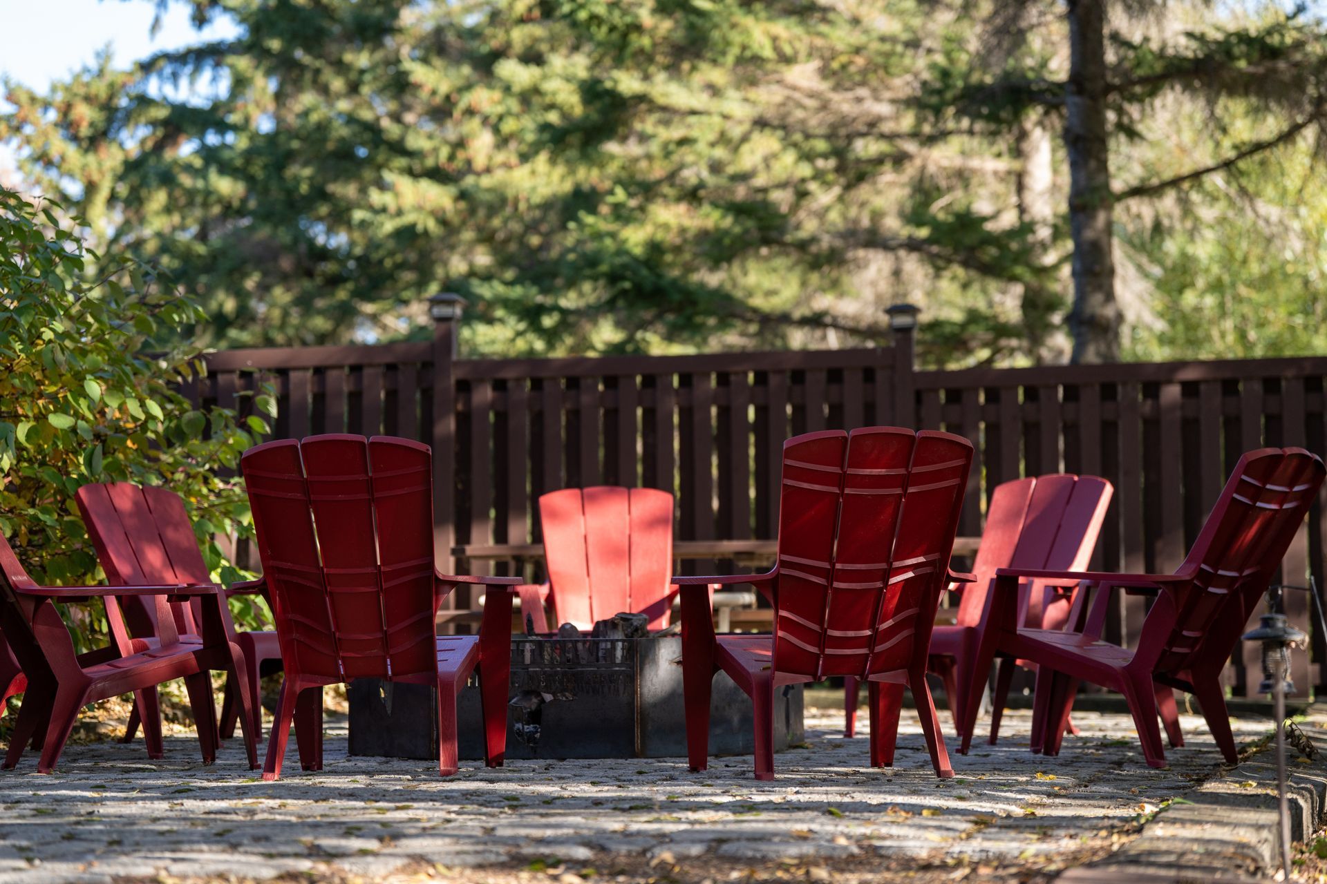 A row of red chairs are sitting around a fire pit.