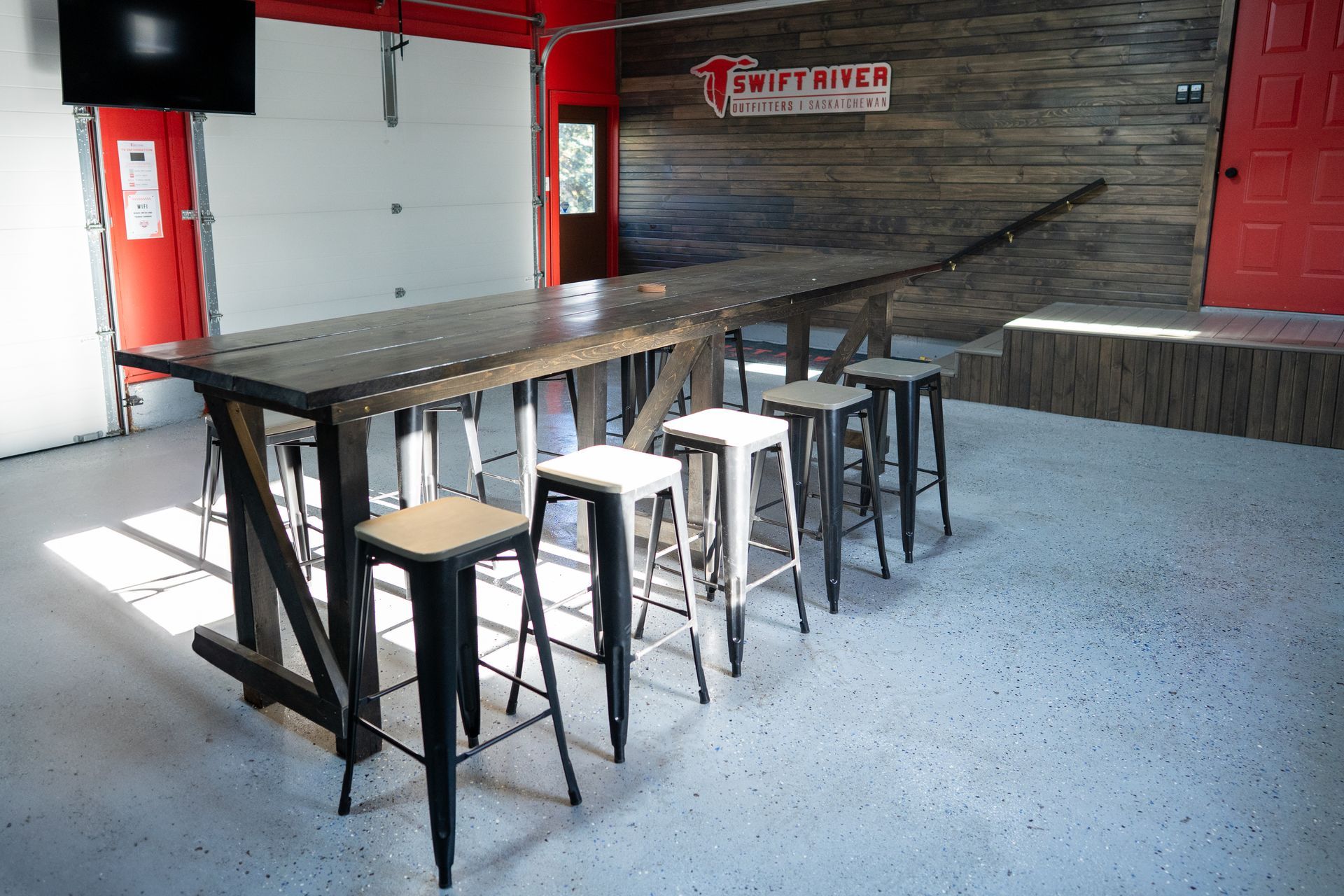 A long wooden table with stools in a garage.