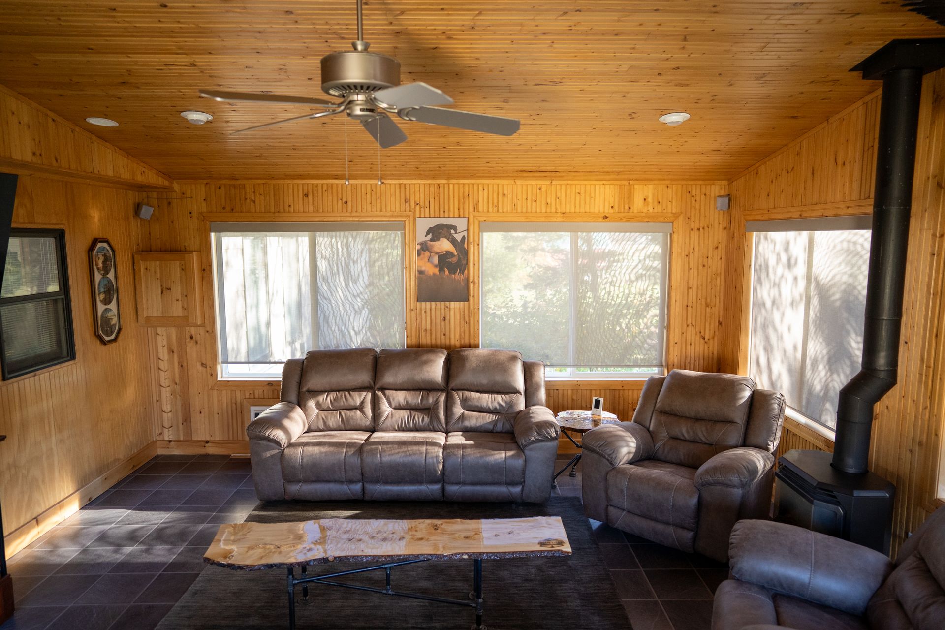 A living room with a couch , chairs , and a ceiling fan.