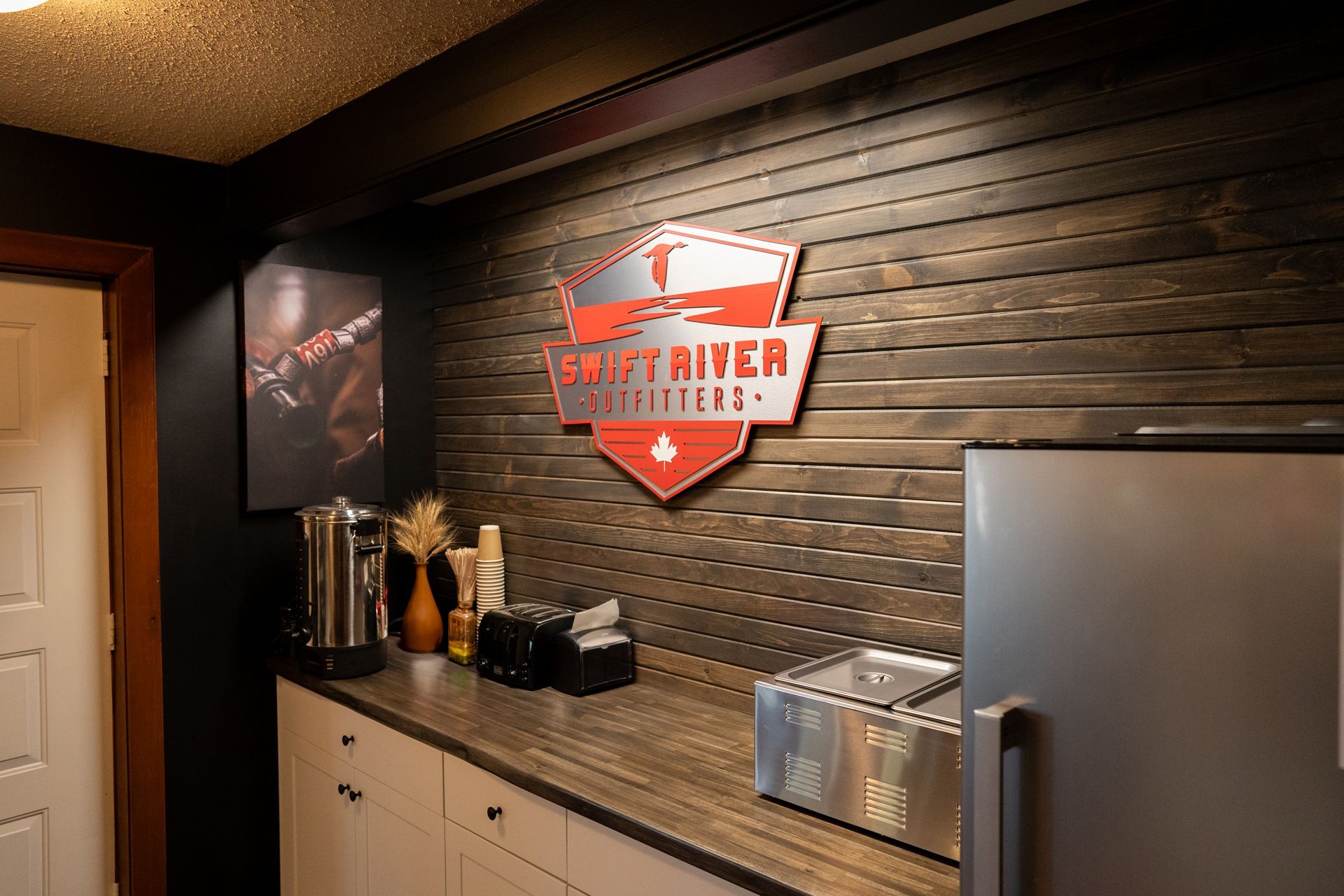 A kitchen with a refrigerator and a sign on the wall.
