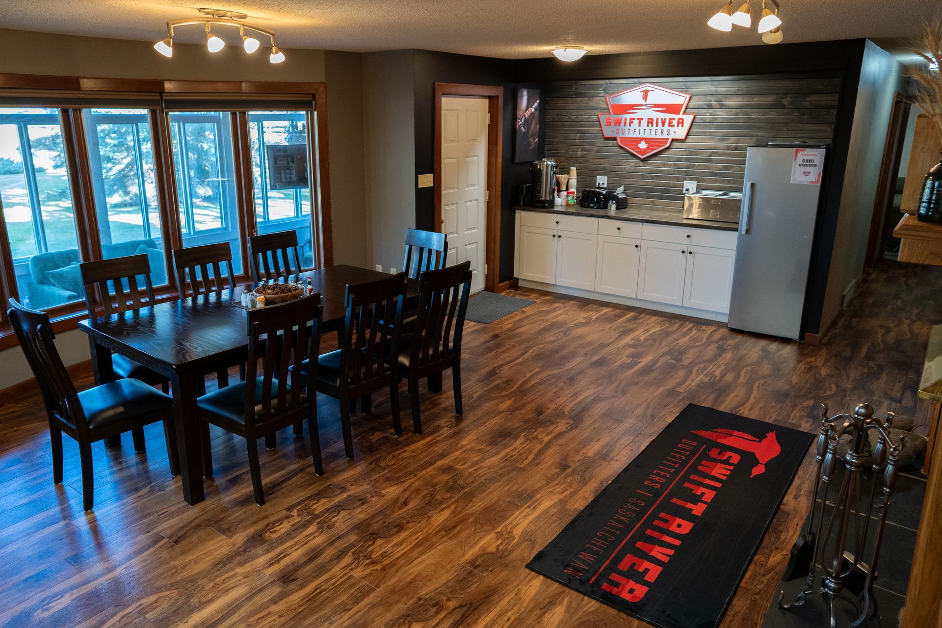 A dining room with a table and chairs and a kitchen.