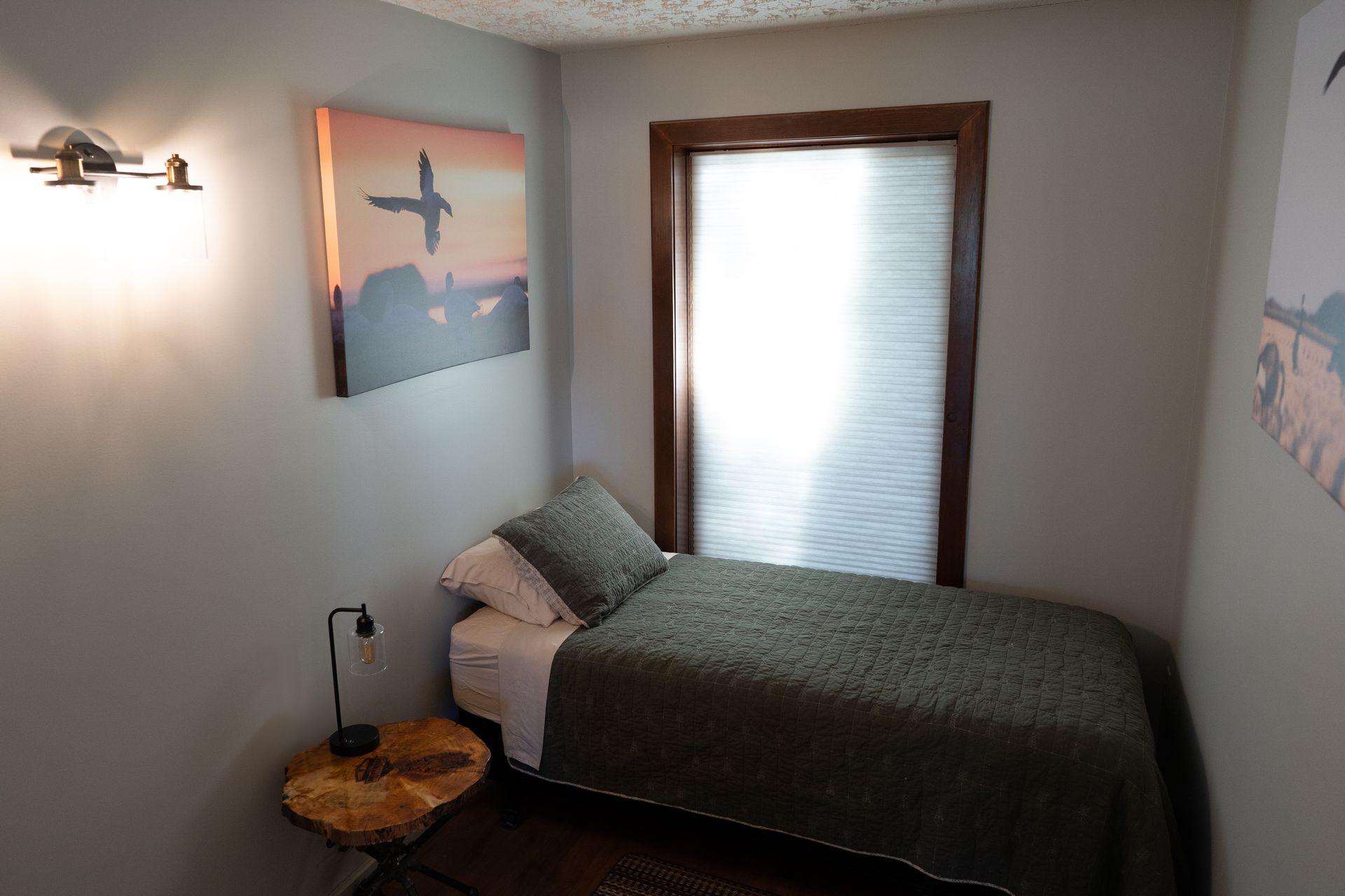 A bedroom with a single bed and a painting on the wall.
