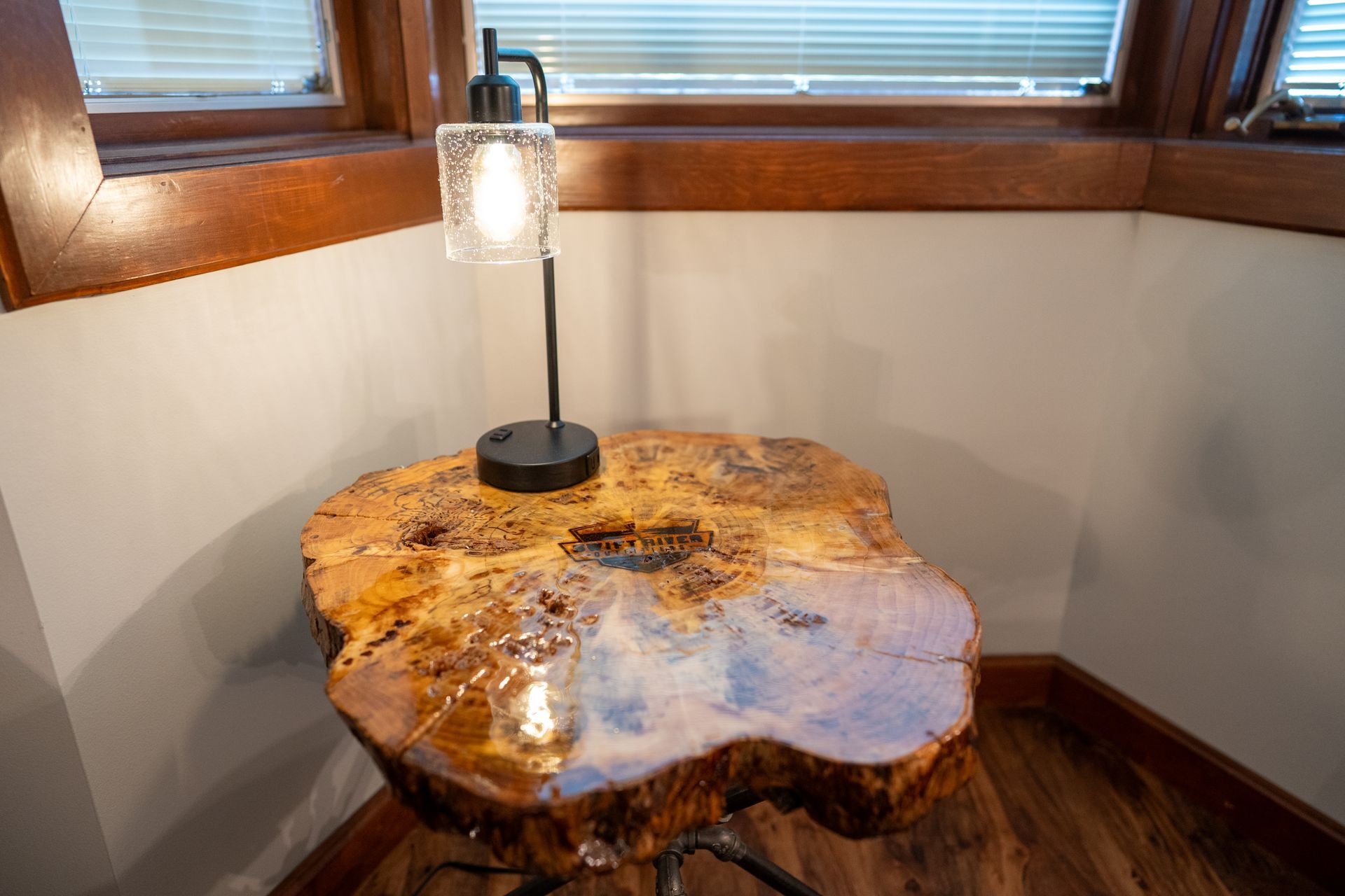 A wooden table with a lamp on it in a room next to a window.
