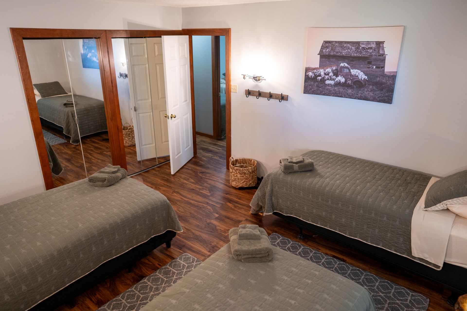 A bedroom with three beds and a large mirror.