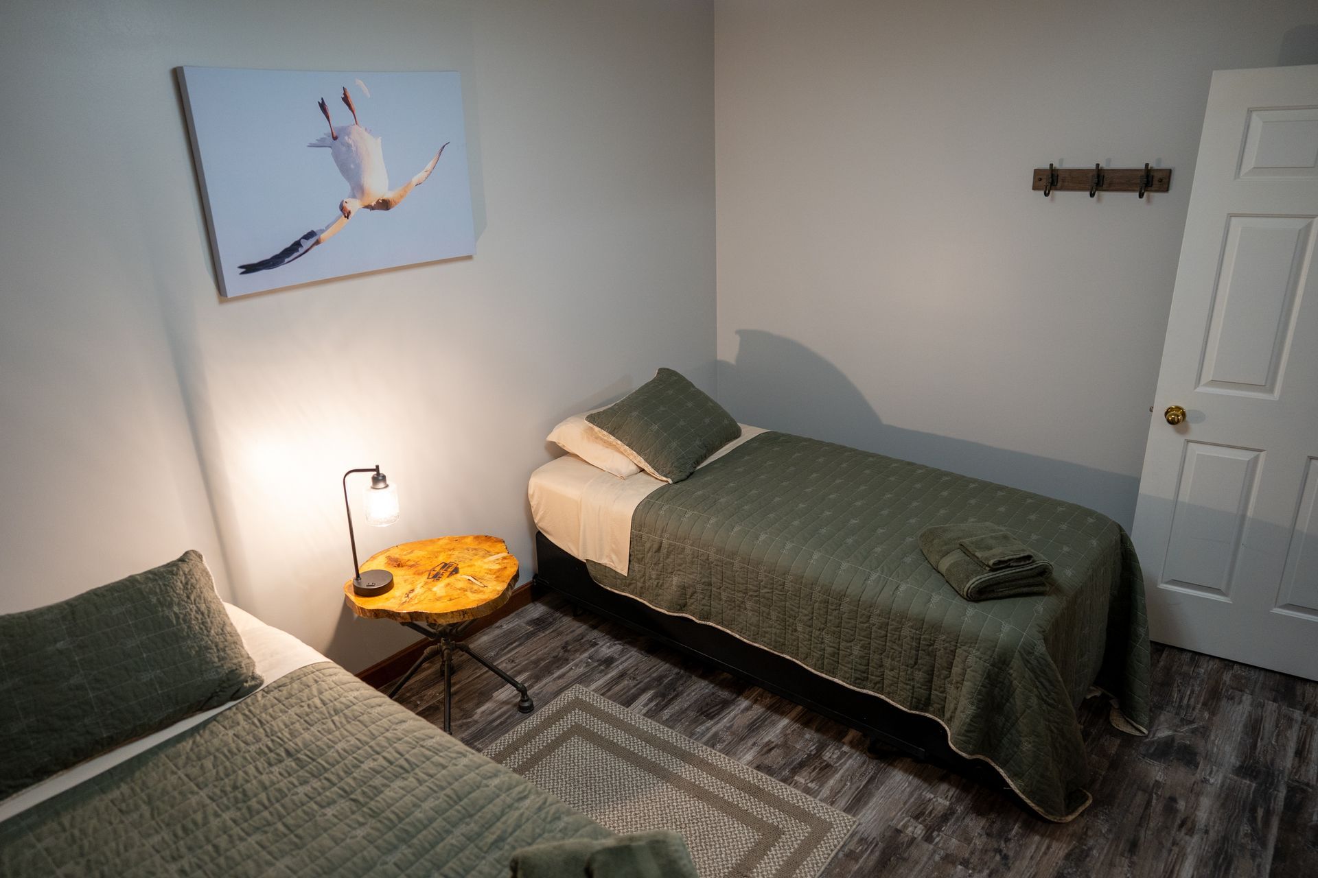A bedroom with two beds and a painting on the wall.