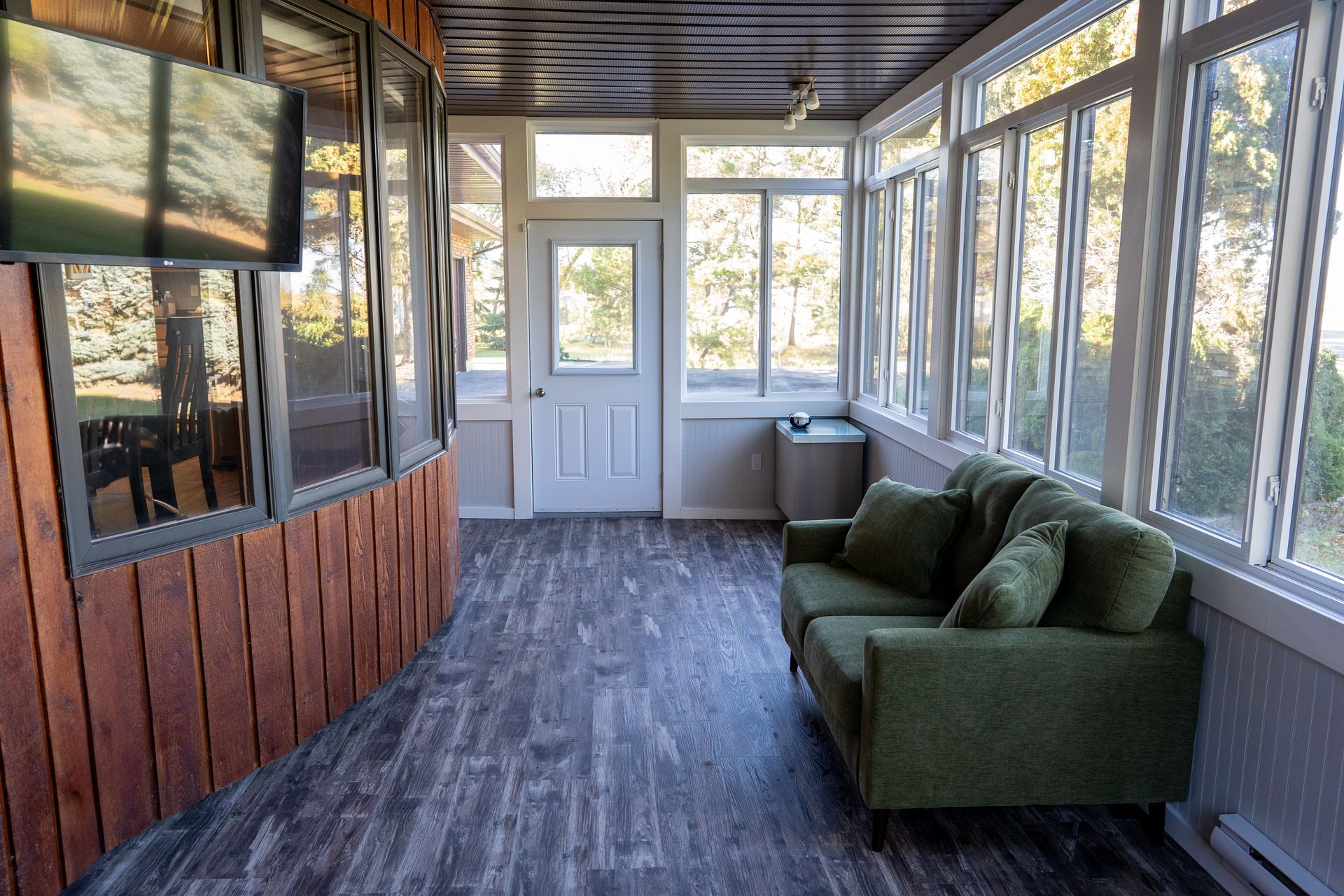 A living room with a green couch and a lot of windows.