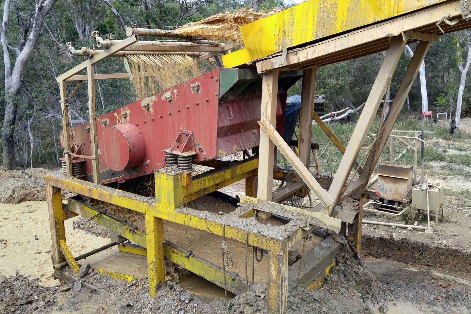 A large machine is sitting in the middle of a dirt field.