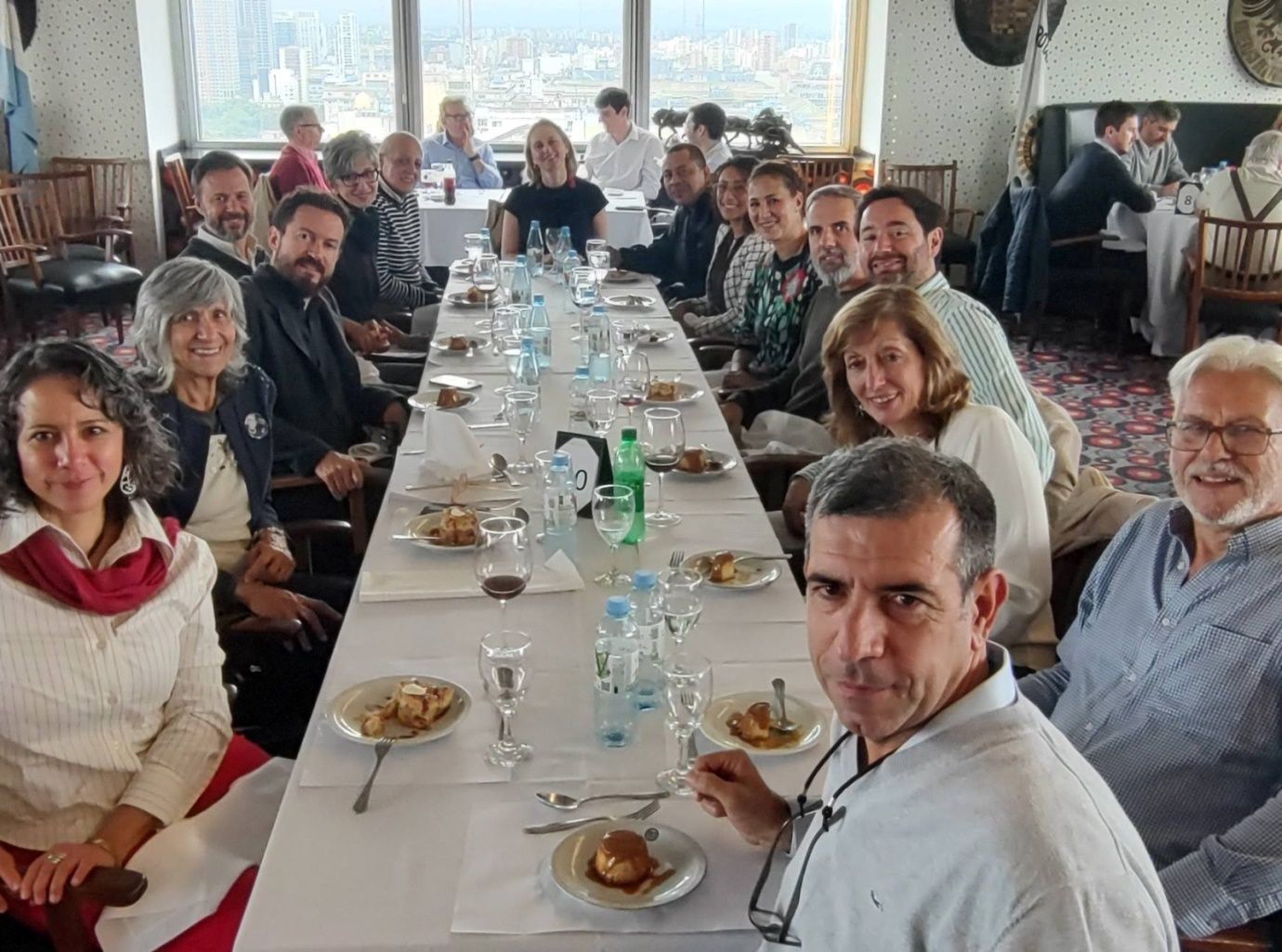 Un grupo de personas está sentado en una mesa larga con platos de comida.