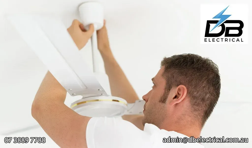 A Man Is Working On A Ceiling Fan With A DB Electrical Logo In The Background – Brendale, QLD - DB Electrical
