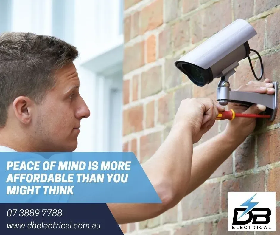 A Man Is Installing A Security Camera On A Brick Wall – Brendale, QLD - DB Electrical