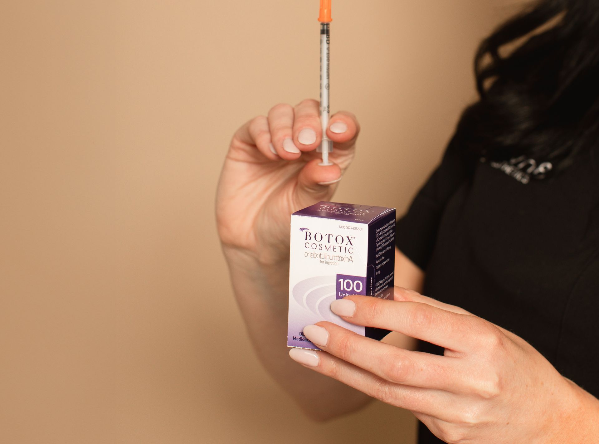A woman is holding a syringe and a box of botox.