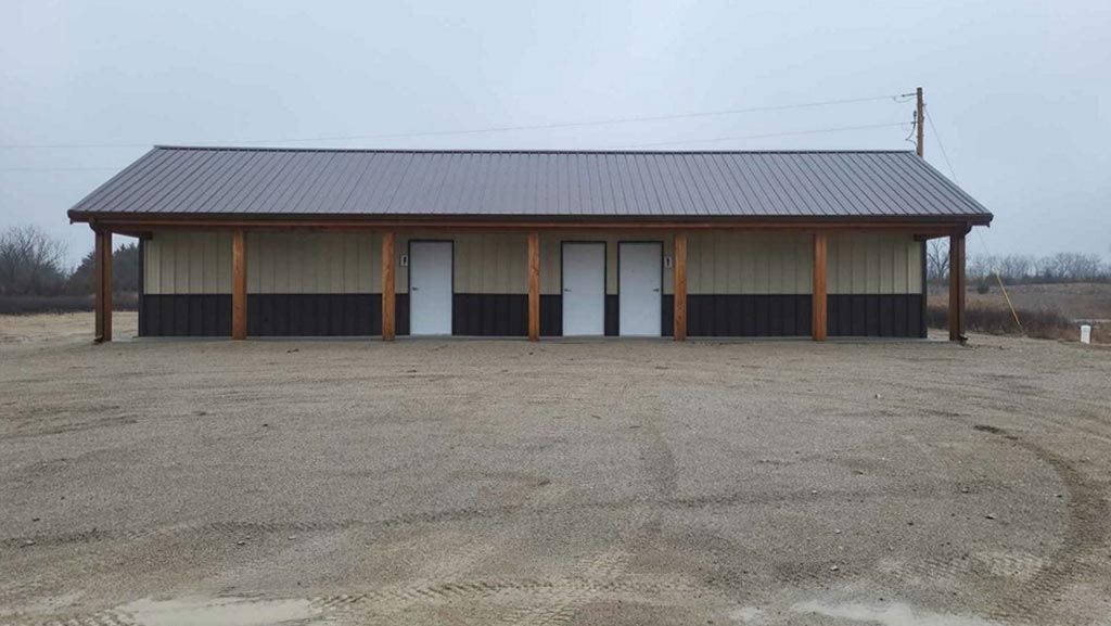 Long, low building with a gray roof in an empty gravel lot on a foggy day