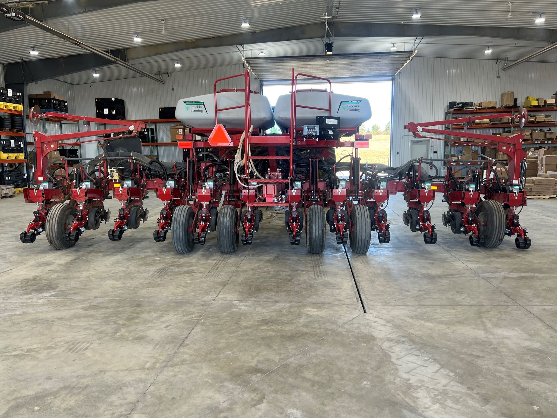 A row of tractors are parked in a warehouse.