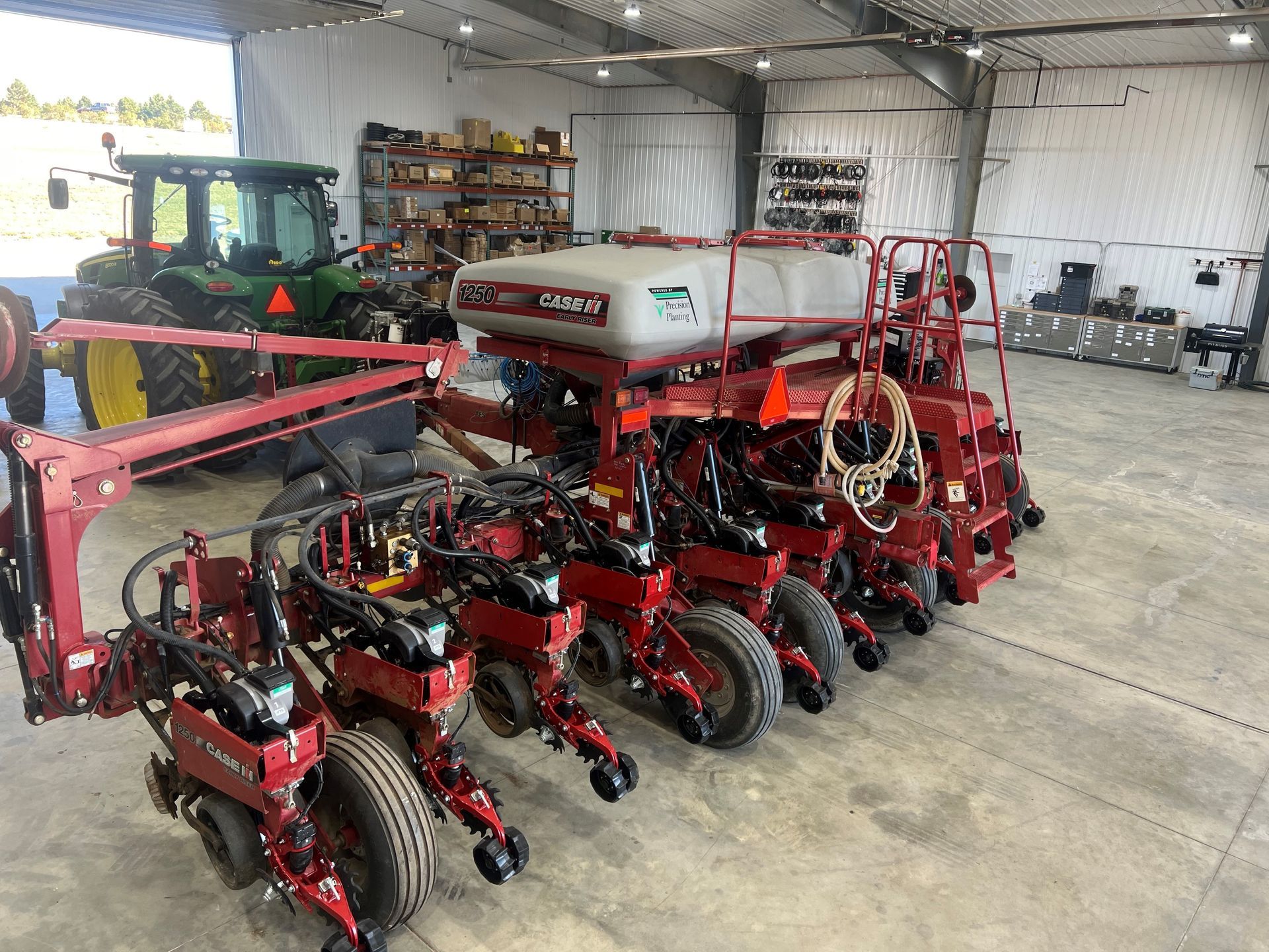 A row of tractors are parked in a warehouse next to each other.