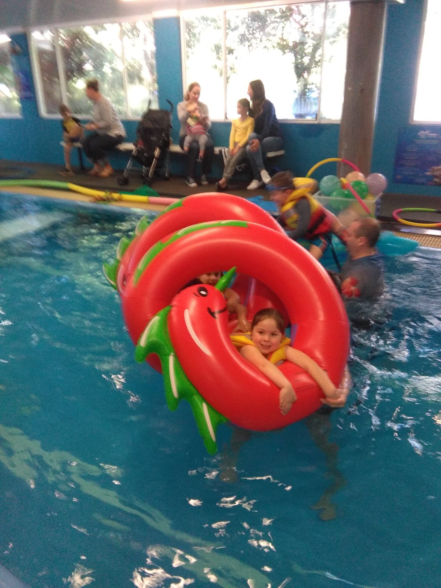 Family Watching Children Playing With Inflatible Dragon At Swim Schoolโ Swim Care Boambee in Coffs Harbour, NSW